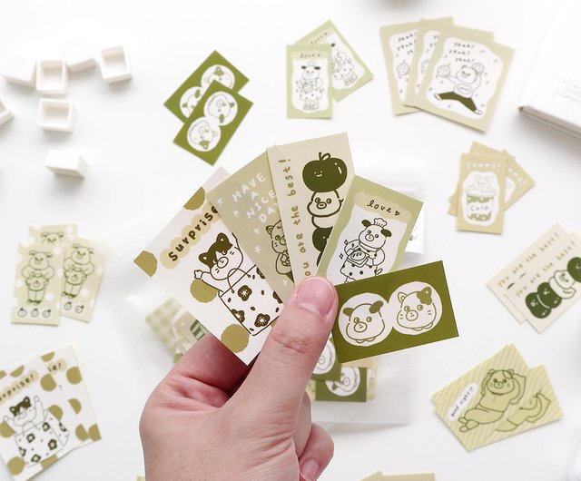 Hand holding a set of small cards with cartoon animal illustrations on a white background.